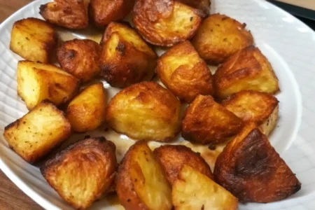 Plate of crispy roast spuds with golden-brown, crunchy edges and fluffy interiors